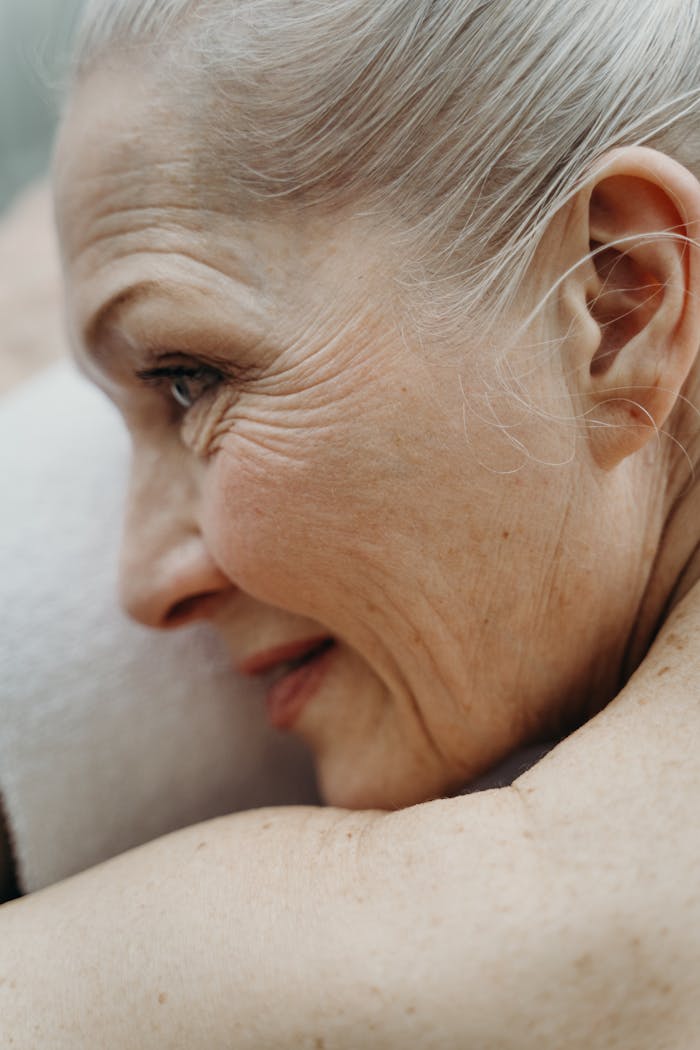 Services-02 Close-up profile of an elderly woman with white hair relaxing on a towel, showcasing natural aging features.